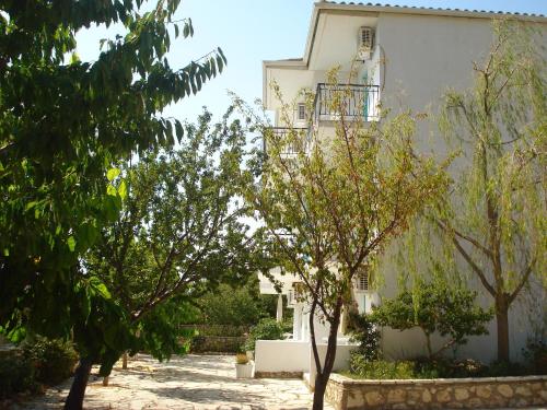 a white building with trees in front of it at Santa Maria Rooms in Agios Nikitas