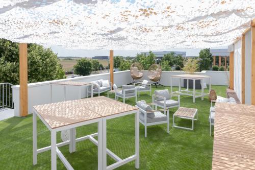 a patio with tables and chairs on the grass at Mercure Chartres Est in Chartres