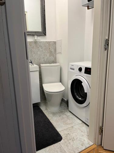 ein Badezimmer mit einem WC, einer Waschmaschine und einem Trockner in der Unterkunft Apartament centrum in Szczytno