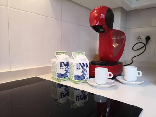 a kitchen counter with a red coffee maker and two cups at A Cabana I in Porriño