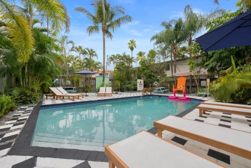 a swimming pool with benches and chairs in a resort at Las Olas Guest House in Fort Lauderdale