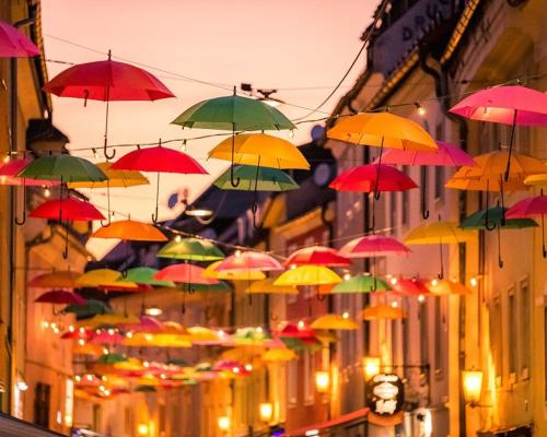 a bunch of colorful umbrellas hanging from buildings at HOSTEL LOVELY ROOMS CITY CENTER, shared Bathroom in Villach