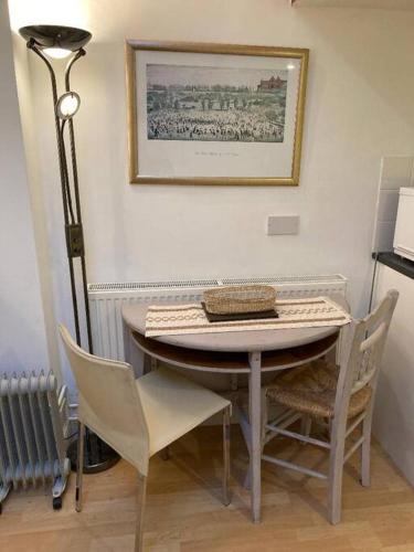 a dining room table with chairs and a picture on the wall at Studio Annexe with separate shower room in Broadhempston