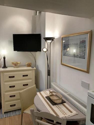 a living room with a table and a television on the wall at Studio Annexe with separate shower room in Broadhempston