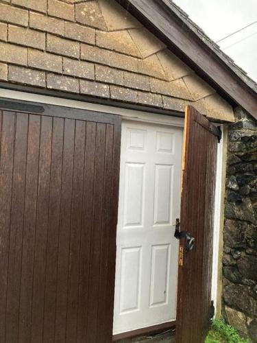 a garage with a white door and a brick building at Studio Annexe with separate shower room in Broadhempston