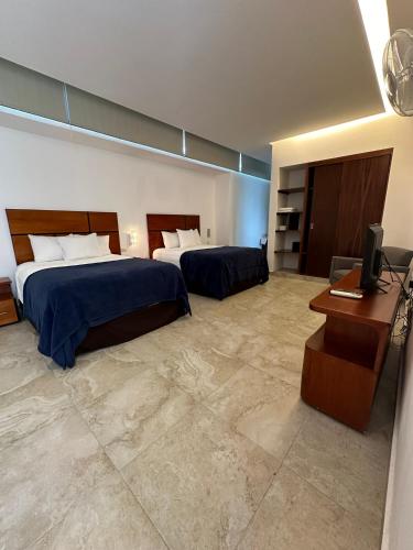 a hotel room with two beds and a desk at Hotel Boutique Zoren in Tulum