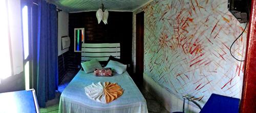 a bedroom with a bed with a painting on the wall at Pousada Suites Praia de Costazul in Rio das Ostras