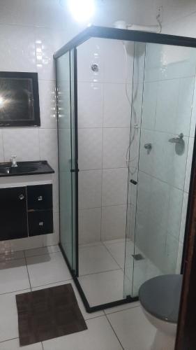 a bathroom with a glass shower with a sink at Pousada Suites Praia de Costazul in Rio das Ostras
