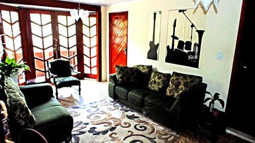 a living room with a couch and a chair at Pousada Suites Praia de Costazul in Rio das Ostras