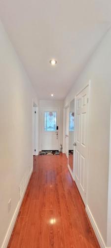 an empty living room with white walls and wood floors at Main Floor Spacious Room in Toronto in Toronto
