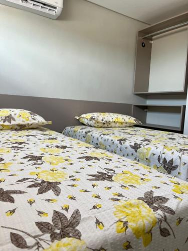 two beds in a room with flowers and butterflies at Pousada Prime in Juazeiro do Norte