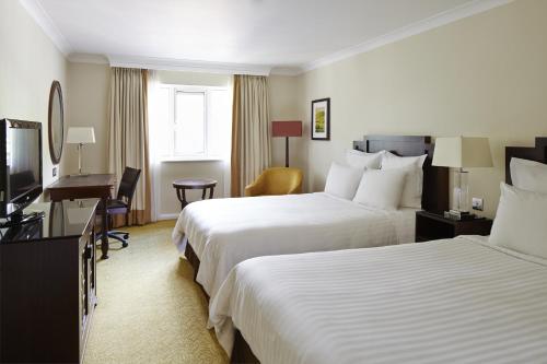 a hotel room with two beds and a flat screen tv at Hollins Hall Hotel, Golf & Country Club in Bradford