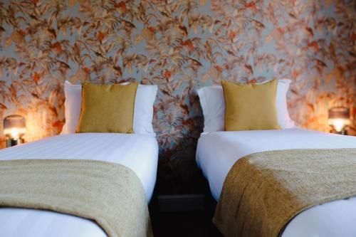two beds in a room with a floral wallpaper at Orange Grove Hotel & Gardens in Southampton