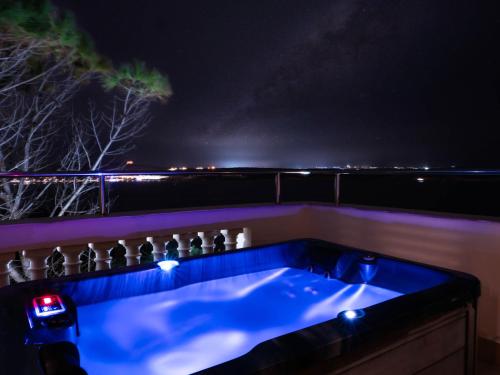 a jacuzzi tub at night with lights on the side at Villa Palma - Sunset Sea Views with Pool, Jacuzzi, Sauna and Games Room in Mellieħa
