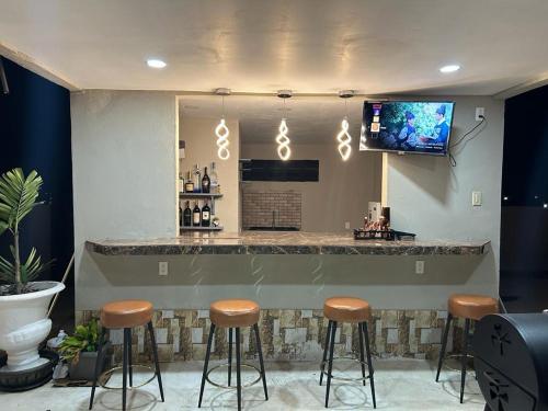 a bar with stools and a tv on a wall at Malik SuitesGY 