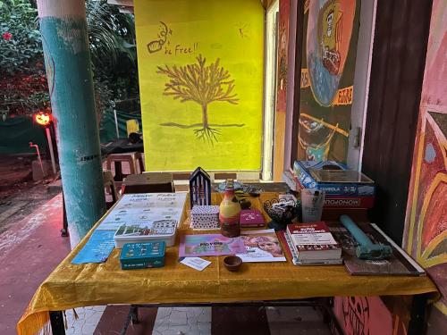 una mesa con libros y otros artículos. en The Last Stop Backpackers Hostel, en Auroville