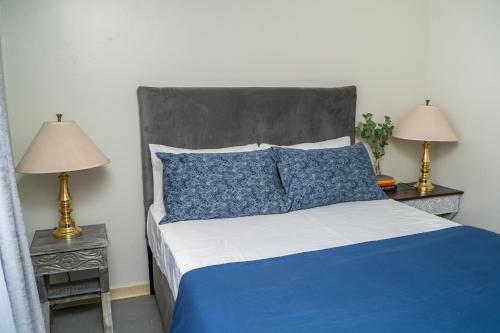 Airport Oasis: 3 bed apartment في نيروبي: غرفة نوم بسرير ازرق وابيض ومصباحين