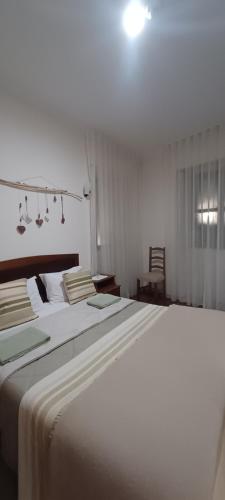 um quarto branco com uma grande cama branca com lençóis brancos em Residencialusobrasileira em Leça da Palmeira