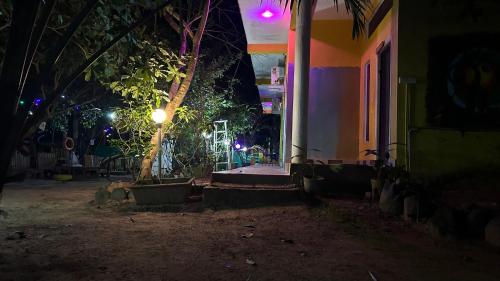 una casa con porche por la noche con luces en The Last Stop Backpackers Hostel, en Auroville