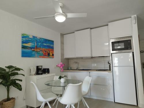 uma cozinha com armários brancos e uma mesa e cadeiras em ATLANTERRA PUEBLO em Zahara de los Atunes