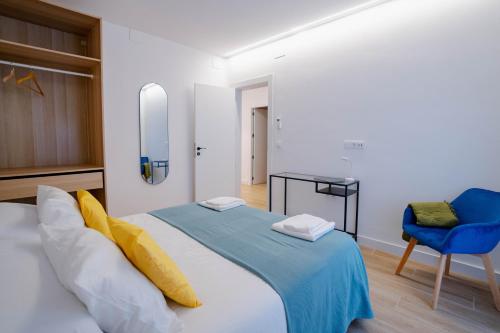 1 dormitorio con 1 cama y 1 silla azul en Apartamentos TriBeCa Centro I, en Albacete