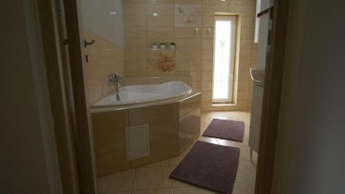 a bathroom with a tub and a sink and a window at Kapolcs Vendégház in Kapolcs