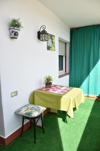 una mesa y una silla en una habitación con alfombra verde en Piso céntrico for2 cerca Barcelona LA CASA DE SONIA en Vilanova i la Geltrú