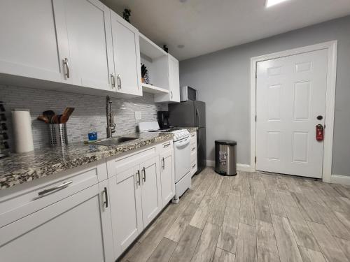 a kitchen with white cabinets and wooden floors at Barefoot mailman motel in Lantana