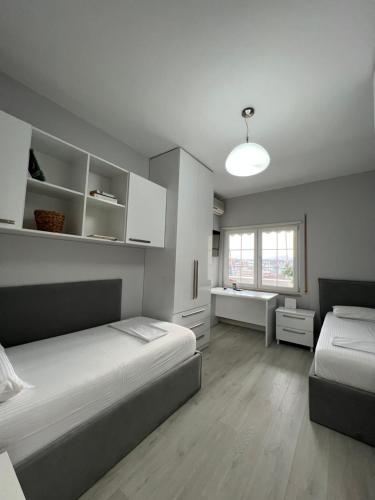 1 dormitorio con 2 camas, escritorio y ventana en Tirana Gallery Apartment - City Center View, en Tirana