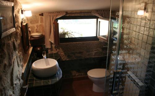 baño con aseo y lavabo y ventana en A Casa de Filomena en Boiro