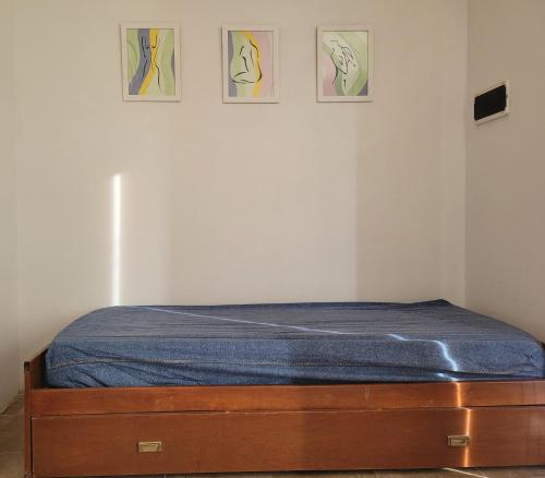 a bed in a room with three paintings on the wall at LAUSITA in Rawson
