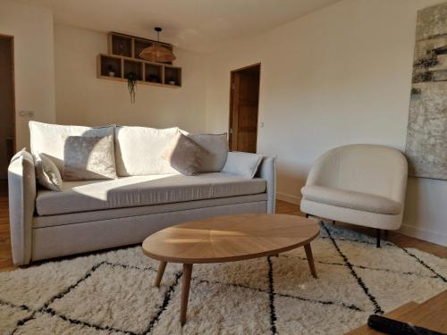 a living room with a couch and a table and a chair at Appartement Enghien-les-Bains à 7 min du Casino Barrière in Enghien-les-Bains