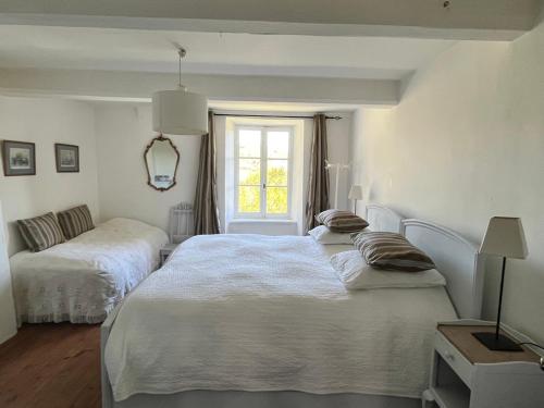 a white bedroom with two beds and a window at Maison vigneronne in Montlaur