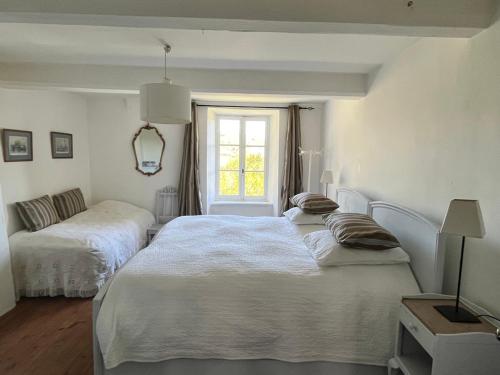 MontlaurにあるMaison vigneronneの白いベッドルーム(ベッド2台、窓付)