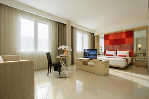 a bedroom with a bed and a desk with a television at Ohana Hotel Kuta in Kuta
