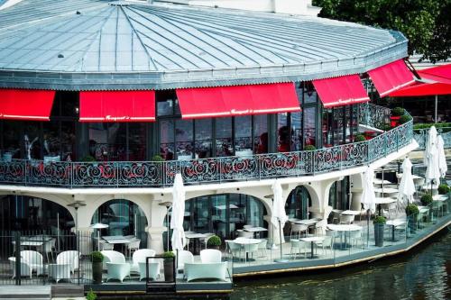 a restaurant on the water with tables and chairs at Appartement Enghien-les-Bains à 7 min du Casino Barrière in Enghien-les-Bains