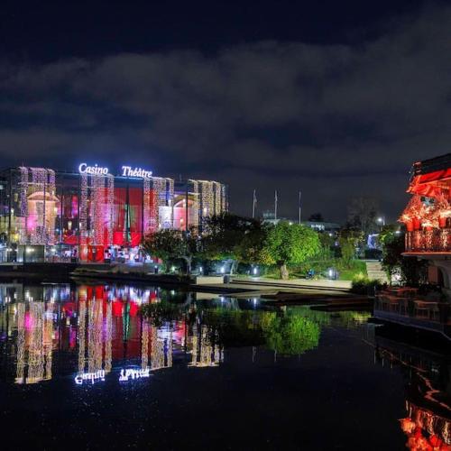 a city lit up at night next to a body of water at Appartement Enghien-les-Bains à 7 min du Casino Barrière in Enghien-les-Bains