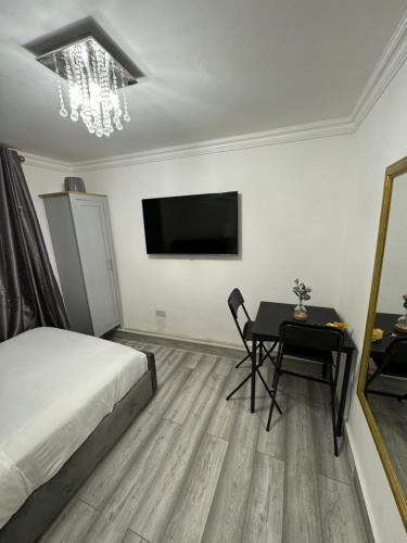 Schlafzimmer mit einem Bett, einem Tisch und einem TV in der Unterkunft Cozy studio for your stay in New Southgate
