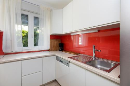 a kitchen with white cabinets and red walls and a sink at Luxury villa Vincent in Slatine