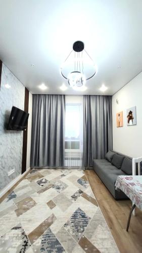 ein Wohnzimmer mit einem Sofa und einem TV in der Unterkunft Евродвушка Тандау in Taldykolʼ