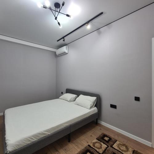 a bed in a room with a white wall at Квартира in Shymkent