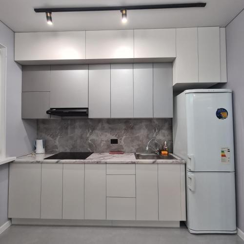a kitchen with white cabinets and a white refrigerator at Квартира in Shymkent