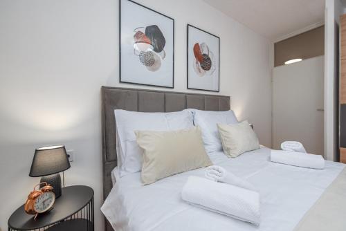 a bedroom with a white bed with a clock on a table at A&M 3 BRIDGE Luxury Center in Zadar