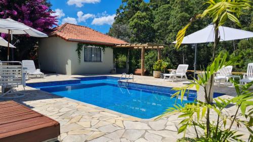 a swimming pool in a backyard with chairs and an umbrella at Chales Vinhas da Harmonia in Cunha
