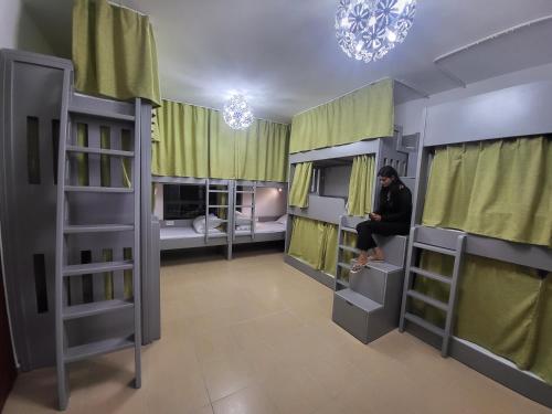 a woman sitting in a room with bunk beds at Atlantis View Hostel in Dubai