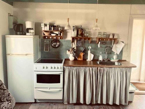 a kitchen with a white stove and a sink at Mormors Gårdhus ved stranden in Rude