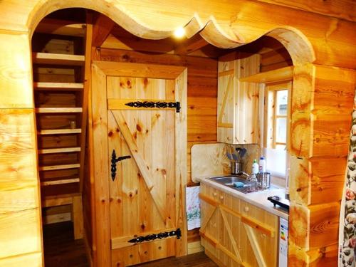 een keuken met een grote houten deur in een huisje bij Chatka Rumcajsa nad Biebrzą 