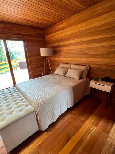 a bedroom with a bed and a wooden wall at Cabana das araucárias in Carlos Barbosa