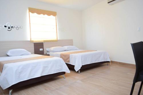 two beds in a room with a window at Hotel Sterling in Cúcuta