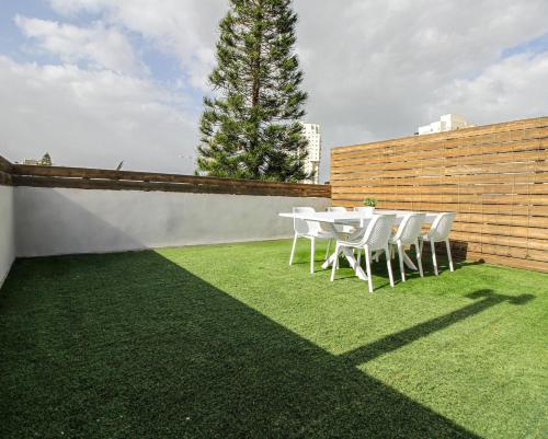 a white table and chairs on a grass field at Rosen Villa at Ramat Hahayal in Tel Aviv